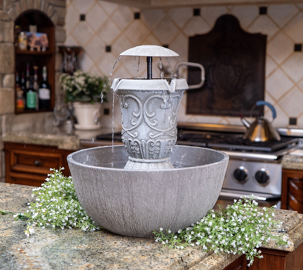 Decorative water fountain on a kitchen counter with flowers around