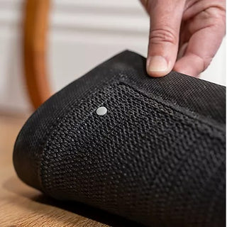 Close-up of a textured black sock with a hand touching it, on a wooden surface.