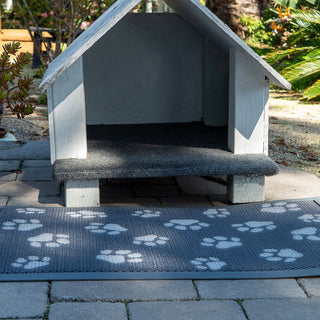 Dog house with a paw print mat on a patio