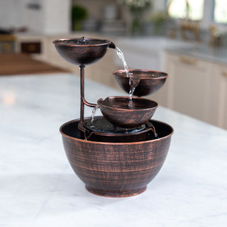 Copper bowl water fountain on a kitchen counter with blurred background