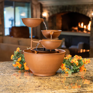 Decorative terracotta water fountain on a table with a warm indoor setting in the background.