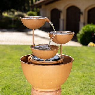 Three-tiered outdoor water fountain with on a grassy area.