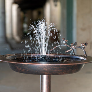 Metallic water fountain with water spraying out, set against a blurred background.