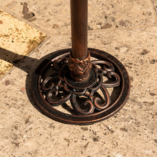 Decorative metal base on a pole with intricate designs, set against a textured stone background.