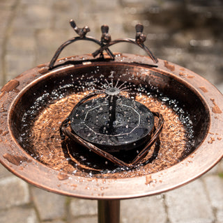 Copper outdoor water feature with water splashing on a blurred background