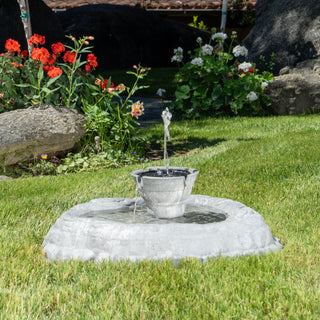 Small garden fountain with flowers and rocks in the background