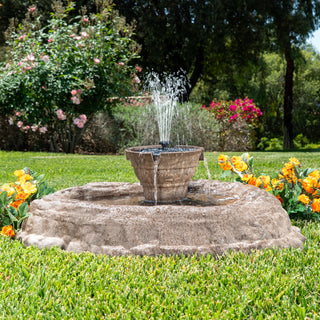 Stone fountain in a garden with flowers and greenery