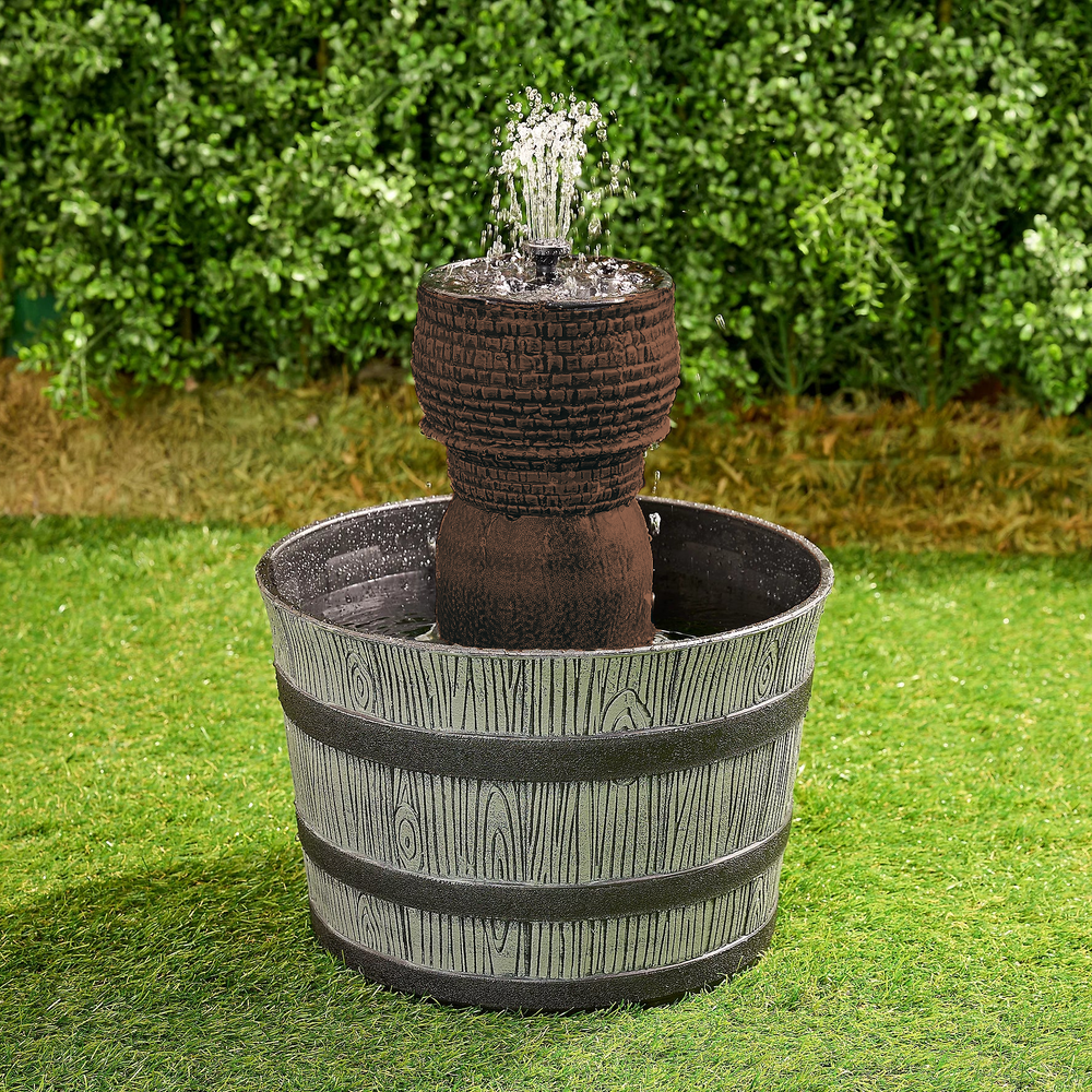 Garden fountain with decorative design on grass and greenery background
